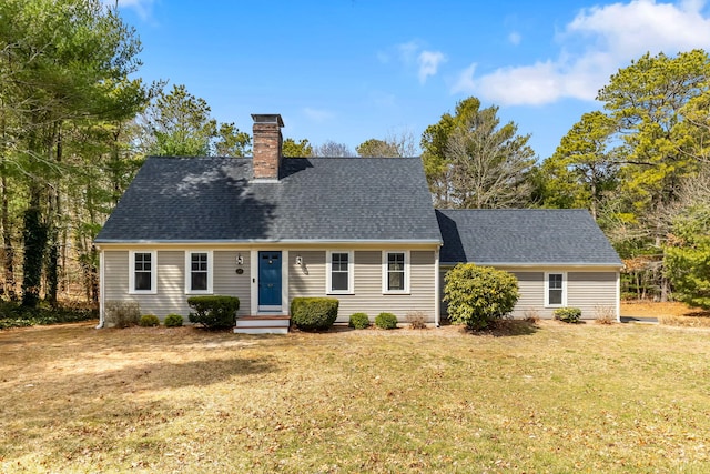 new england style home featuring a chimney, a front yard, and roof with shingles