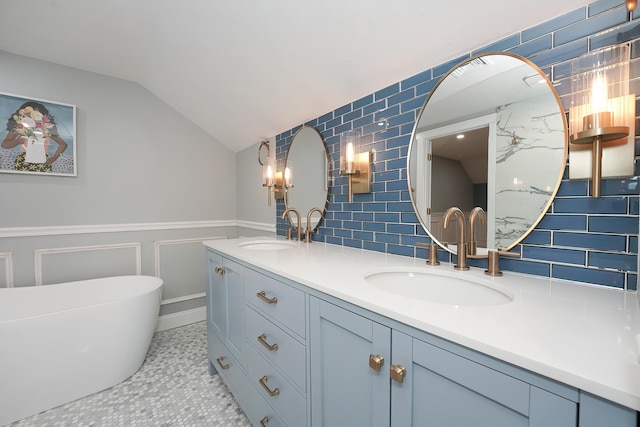 240 Oak St, Centerville, MA 02632 - bathroom featuring double vanity, vaulted ceiling, a freestanding tub, decorative backsplash, and wainscoting
