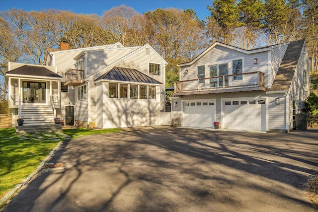 118 Driftwood Ln, South Yarmouth, MA 02664 - view of front of house featuring a balcony, asphalt driveway, a chimney, a garage, and a standing seam roof