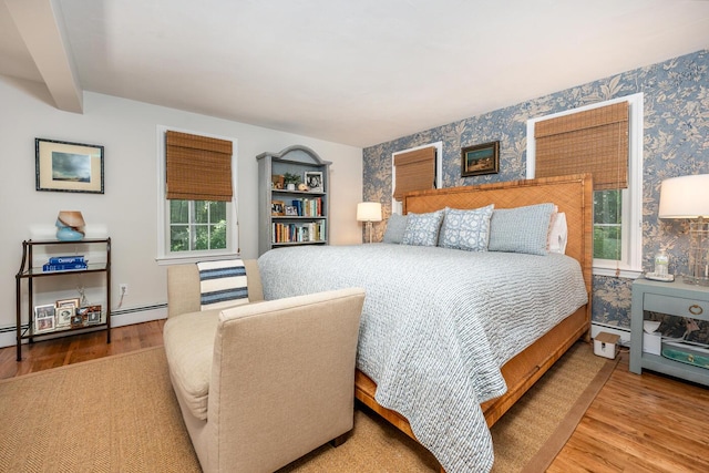 bedroom with a baseboard radiator, hardwood / wood-style floors, and beam ceiling