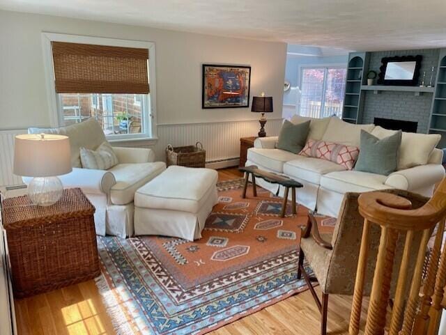 44 Leeward Run, South Yarmouth, MA 02664 - living area featuring wood finished floors, a wainscoted wall, a brick fireplace, built in shelves, and baseboard heating