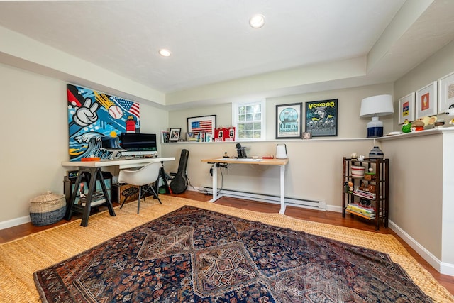 home office with baseboard heating, wood-type flooring, and a tray ceiling