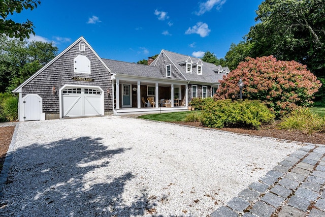 view of front of property with gravel driveway, covered porch, and an attached garage