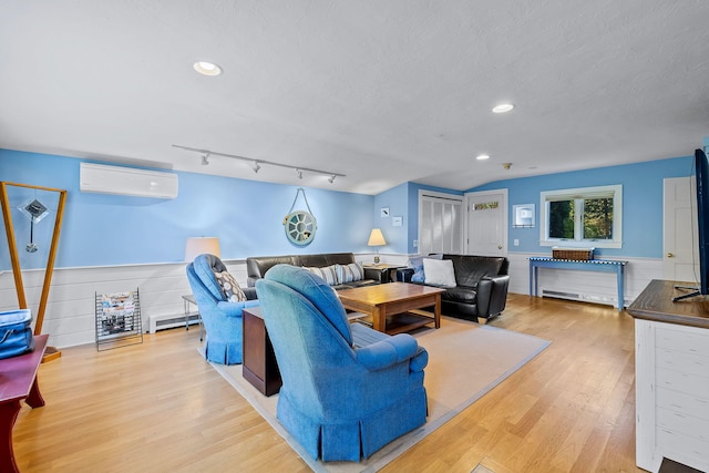 living room with lofted ceiling, a wall mounted AC, a textured ceiling, light wood-type flooring, and a baseboard heating unit