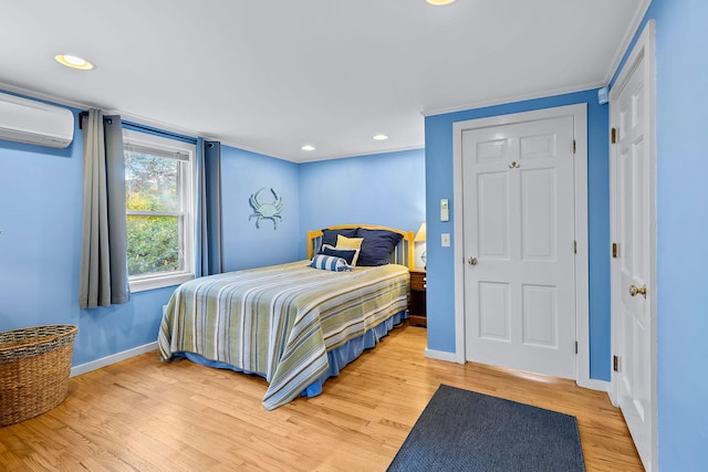 bedroom featuring hardwood / wood-style floors, ornamental molding, and a wall mounted AC