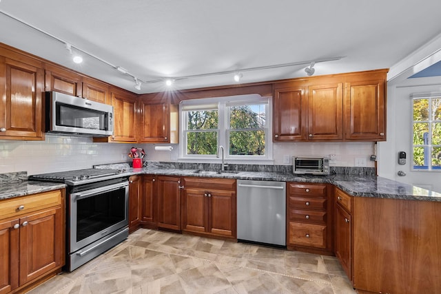 kitchen featuring stainless steel appliances, sink, decorative backsplash, and dark stone counters