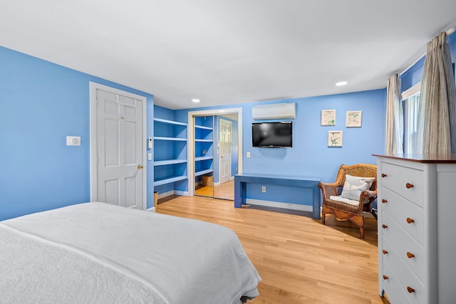 bedroom featuring a wall mounted AC and light hardwood / wood-style flooring