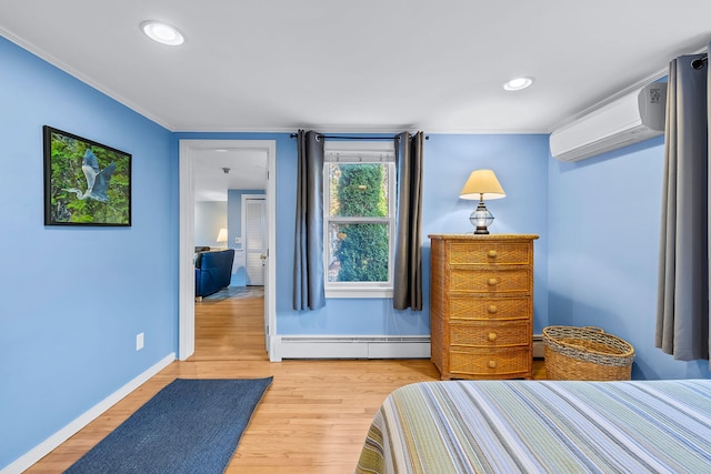 bedroom featuring crown molding, a baseboard heating unit, a wall mounted air conditioner, and light hardwood / wood-style flooring