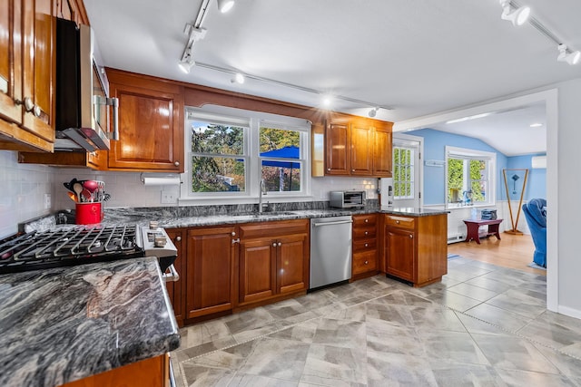 kitchen featuring lofted ceiling, sink, dark stone countertops, kitchen peninsula, and stainless steel appliances