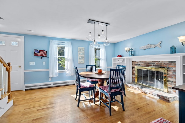 dining room featuring a baseboard heating unit, light hardwood / wood-style flooring, and a fireplace