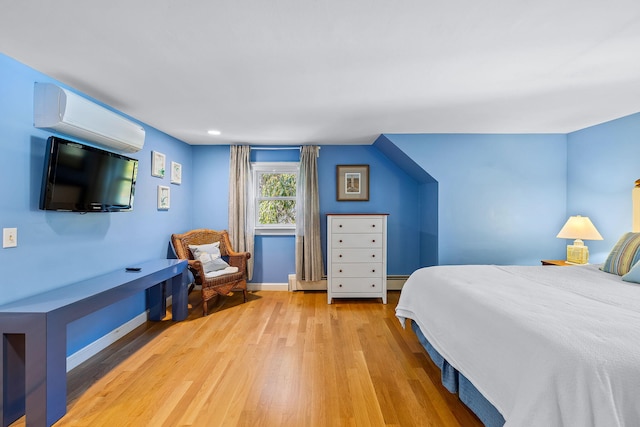 bedroom featuring a baseboard heating unit, a wall unit AC, and light wood-type flooring