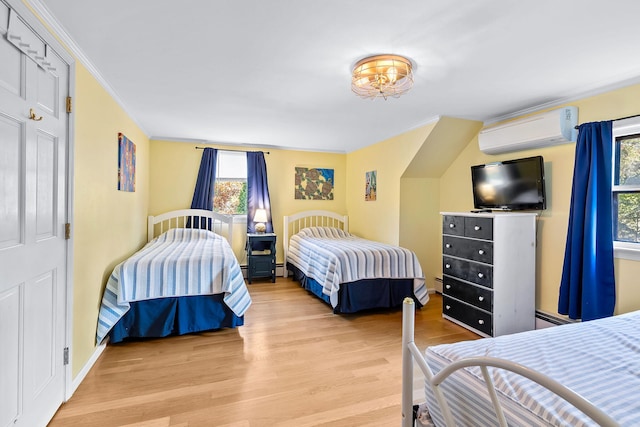 bedroom with crown molding, a wall mounted air conditioner, and light hardwood / wood-style floors