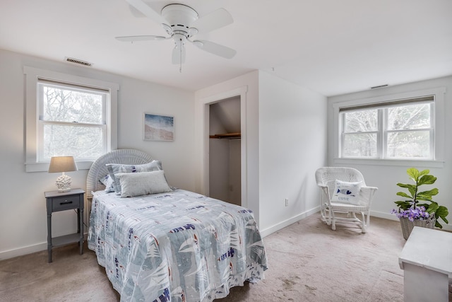 bedroom featuring light colored carpet, multiple windows, baseboards, and ceiling fan
