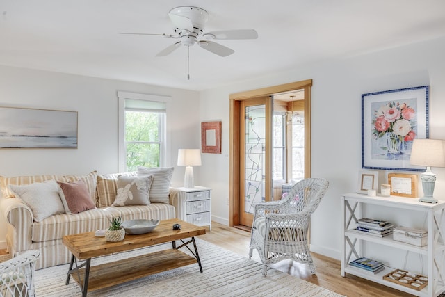 living area with a ceiling fan, baseboards, and light wood-style floors