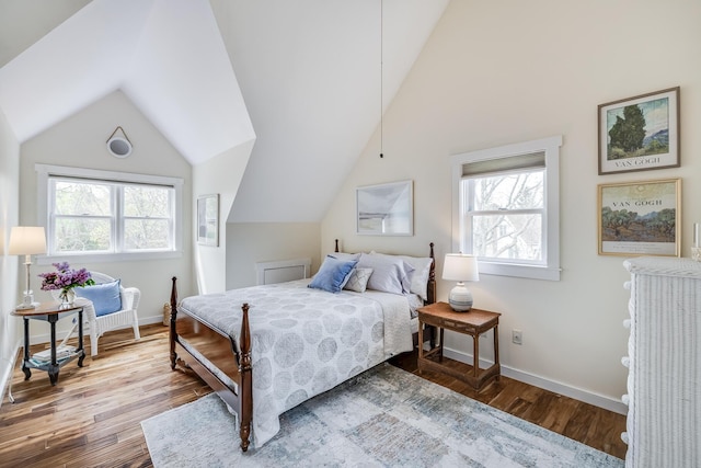 bedroom featuring vaulted ceiling, multiple windows, wood finished floors, and baseboards