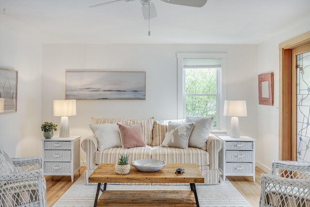 living area featuring a ceiling fan, light wood-style flooring, and baseboards