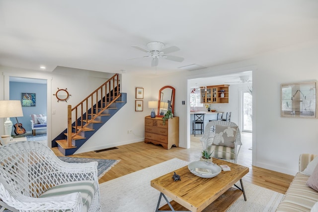 living room featuring ceiling fan, stairs, baseboards, wood finished floors, and recessed lighting