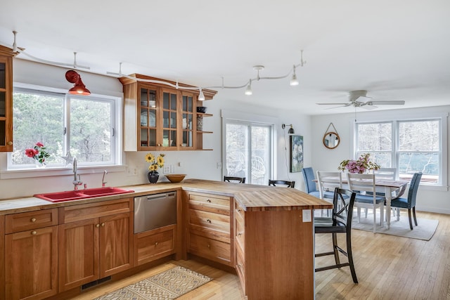 kitchen featuring stainless steel dishwasher, a sink, a peninsula, a breakfast bar, and healthy amount of natural light