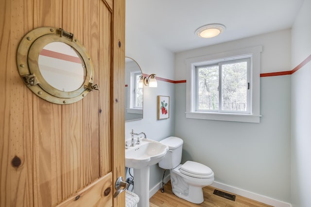 bathroom with toilet, wood finished floors, and baseboards