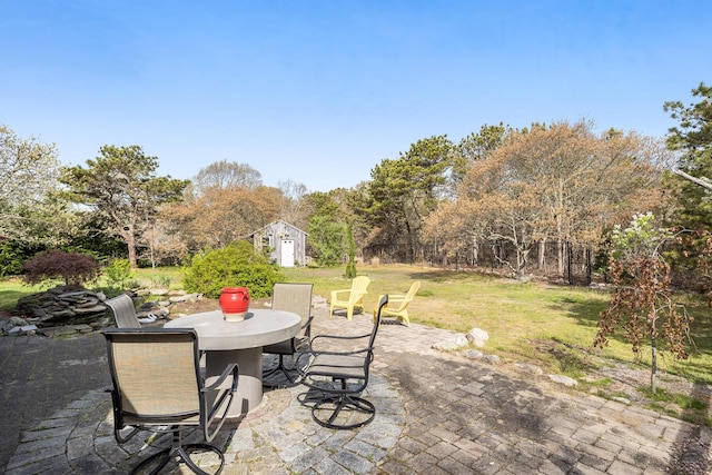 view of patio / terrace featuring outdoor dining space, an outdoor structure, and a storage shed