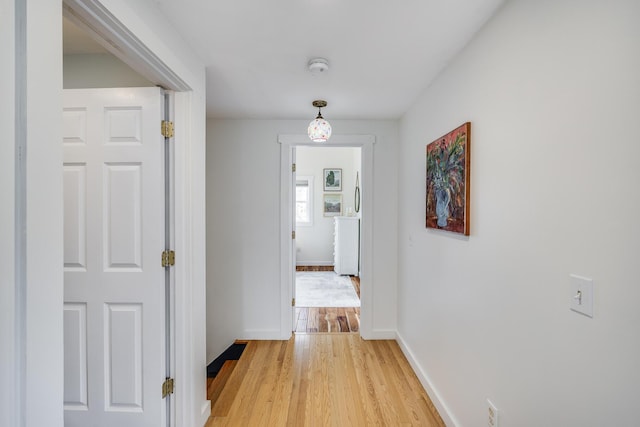 corridor featuring light wood-style floors and baseboards