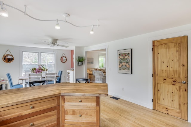 kitchen with ceiling fan, light wood-style flooring, baseboards, and wood counters
