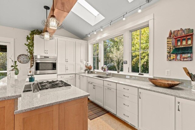 kitchen with light stone counters, white cabinetry, hanging light fixtures, and appliances with stainless steel finishes