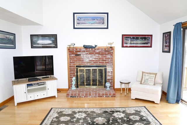 living room with baseboards, a brick fireplace, and wood finished floors