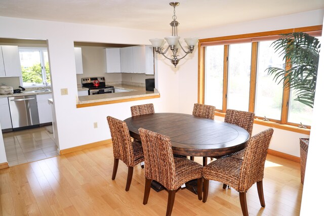 dining space featuring baseboards, light wood finished floors, and a chandelier