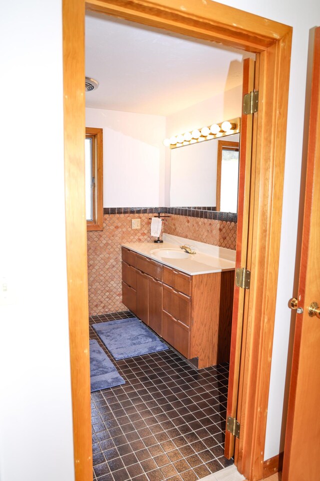 bathroom featuring tile walls, wainscoting, and vanity