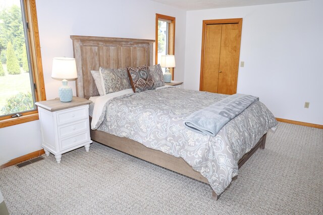 carpeted bedroom featuring baseboards, visible vents, and multiple windows