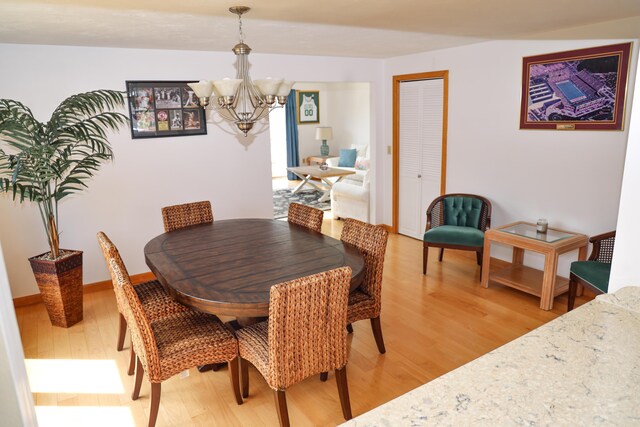 dining area featuring baseboards, an inviting chandelier, and light wood-style flooring