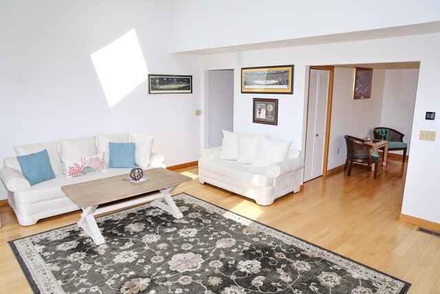 living area with baseboards, visible vents, and wood finished floors