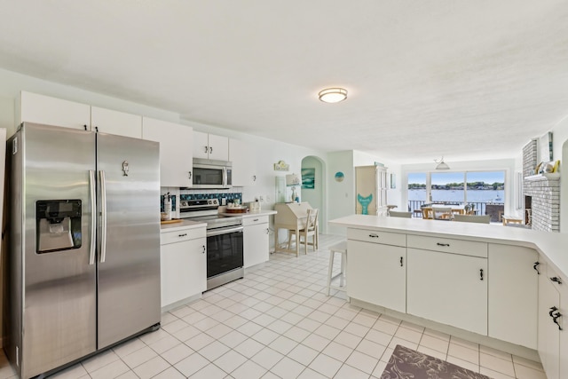 57 Oak St, Wareham, MA 02571 - kitchen featuring appliances with stainless steel finishes, arched walkways, light countertops, tasteful backsplash, and a peninsula