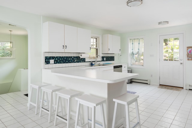 kitchen featuring white cabinets, a kitchen bar, tasteful backsplash, kitchen peninsula, and stainless steel dishwasher