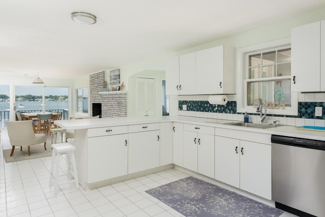 kitchen with white cabinets, dishwasher, decorative backsplash, sink, and kitchen peninsula