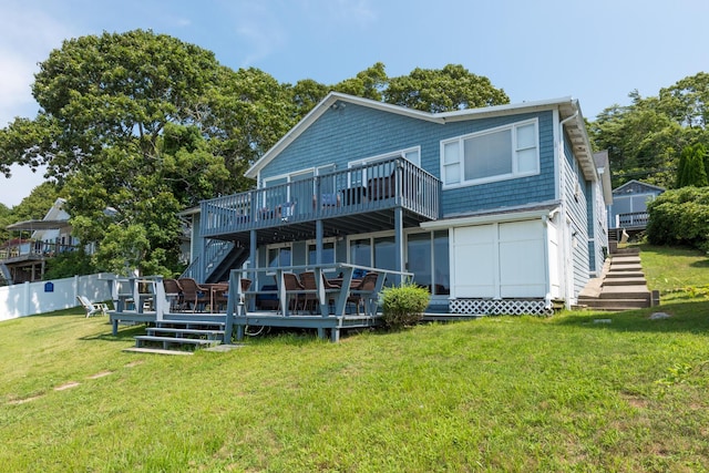 rear view of house featuring a wooden deck and a lawn