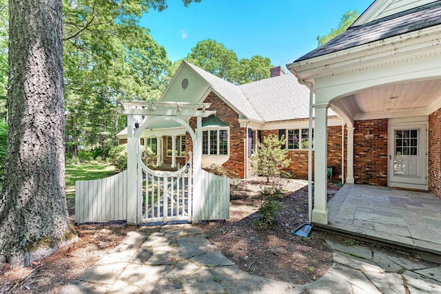 exterior space with a chimney, a shingled roof, and brick siding