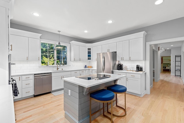 kitchen with light wood-style flooring, a sink, white cabinets, and appliances with stainless steel finishes