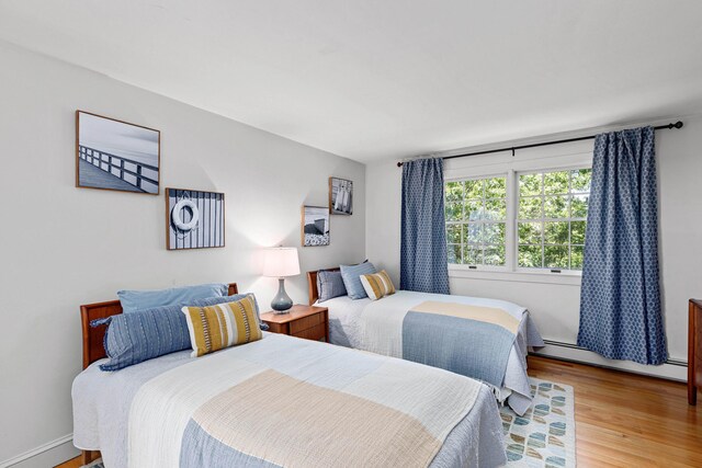 bedroom featuring baseboard heating and wood finished floors