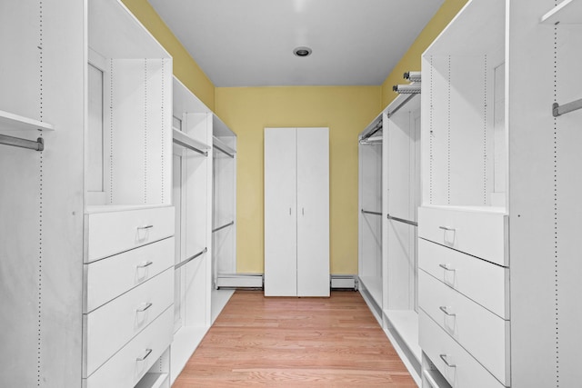 walk in closet featuring baseboard heating, light wood-type flooring, and a baseboard heating unit