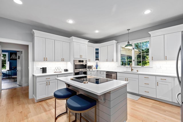 kitchen with a sink, white cabinets, stainless steel appliances, and decorative backsplash