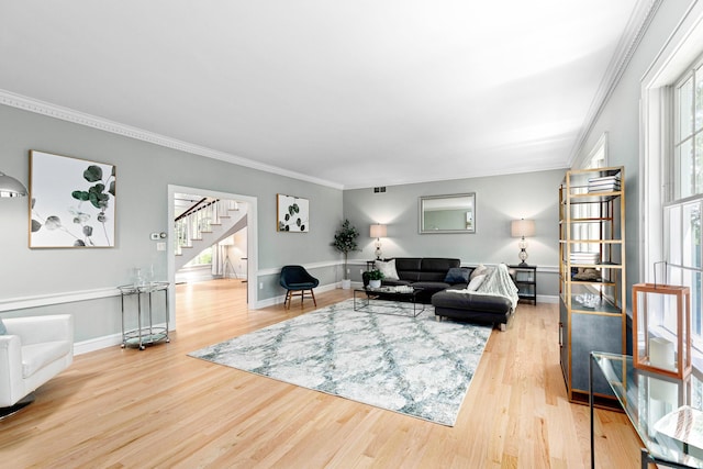 living area featuring light wood-style floors, crown molding, stairs, visible vents, and baseboards