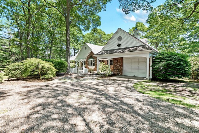 view of front of property featuring driveway, a chimney, a garage, and brick siding