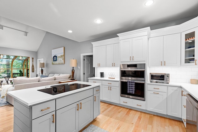 kitchen with light wood finished floors, a kitchen island, a toaster, appliances with stainless steel finishes, and open floor plan