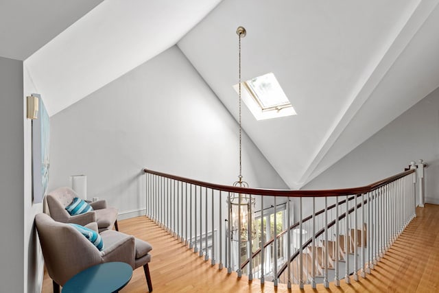 hallway featuring wood finished floors, an upstairs landing, and lofted ceiling with skylight