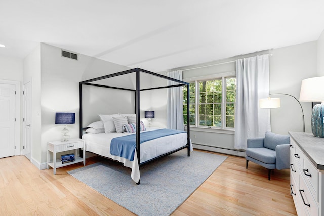 bedroom with visible vents, baseboard heating, and light wood-type flooring