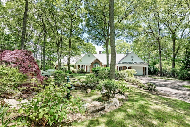 view of front facade featuring driveway, a chimney, and an attached garage