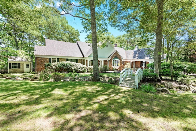 view of front of house with a chimney, a front yard, and brick siding
