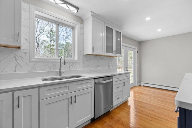 kitchen with a baseboard heating unit, tasteful backsplash, stainless steel dishwasher, and a sink
